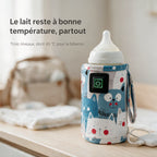 Chauffe-biberon de voyage à motifs chats bleus branché sur une batterie externe, posé sur une table près d'un sac à langer – le lait reste à bonne température, 3 niveaux dont 45 °C
